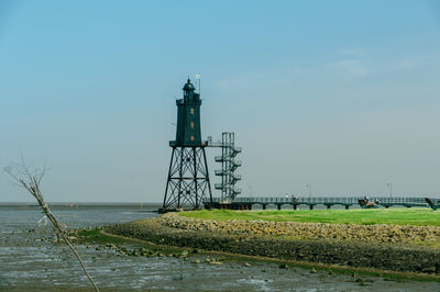 Lighthouse by sea against clear sky