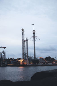 Cranes in river against cloudy sky