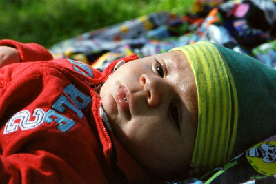 Close-up of cute baby boy lying in park