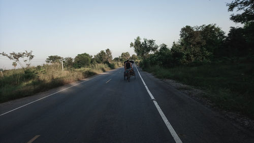 Man riding cart on road against sky