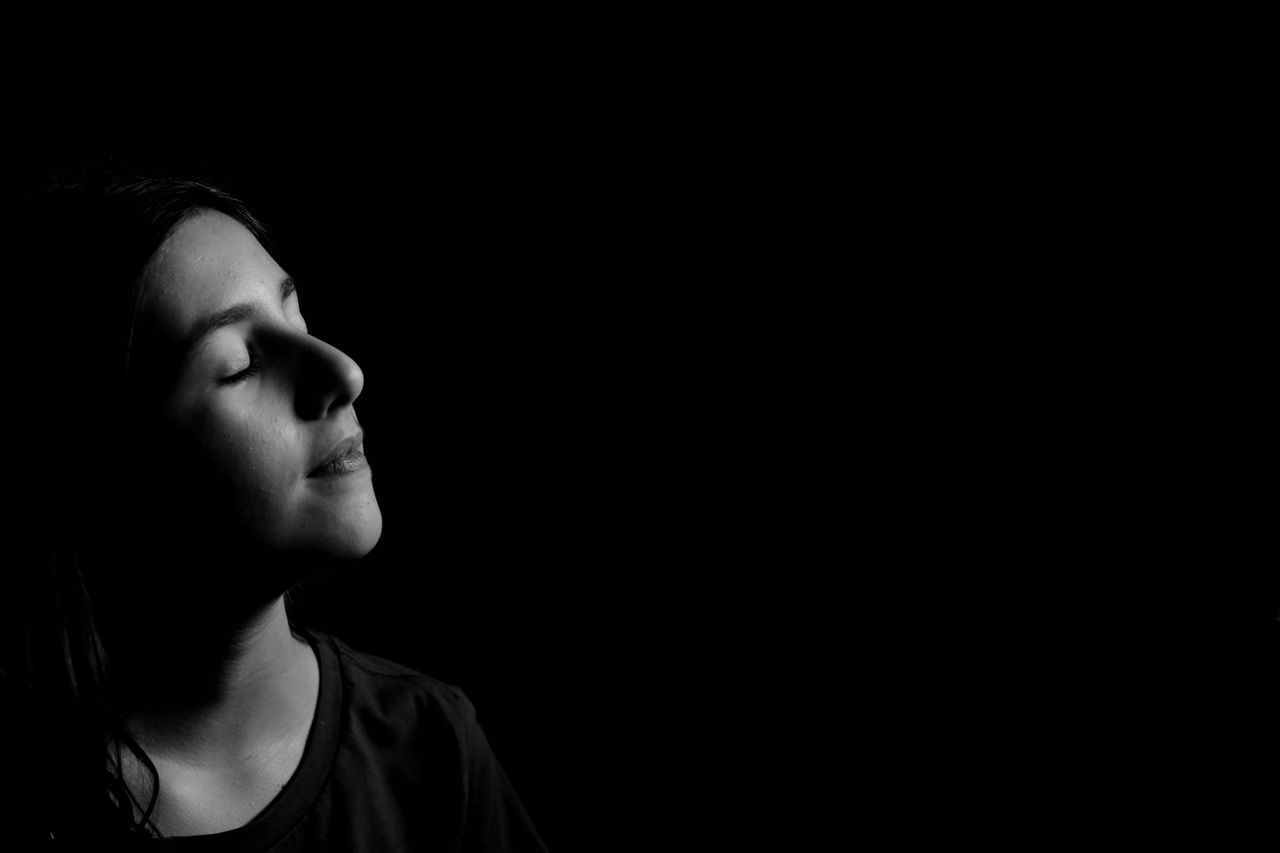 one person, headshot, portrait, copy space, looking, studio shot, black background, contemplation, indoors, child, dark, lifestyles, eyes closed, serious, teenager, looking away, young adult, emotion, adolescence, profile view, depression - sadness, human face