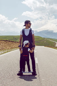 Father son to ride a black skateboard on road against the backdrop of mount everest in the summer