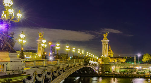 Illuminated bridge over river at night