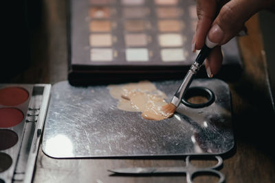 Cropped hand of woman holding paintbrush on table