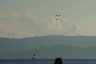 Hot air balloon flying over sea against sky