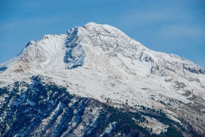 Low angle view of snowcapped mountain against blue sky