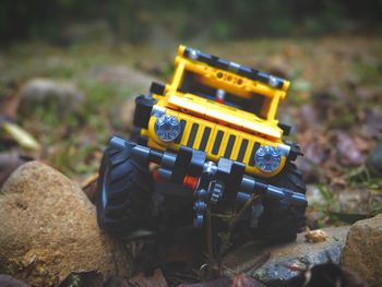 Close-up of yellow toy car on rock