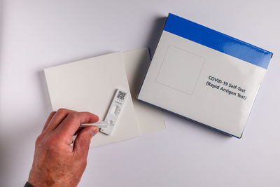 Midsection of person holding paper against white background