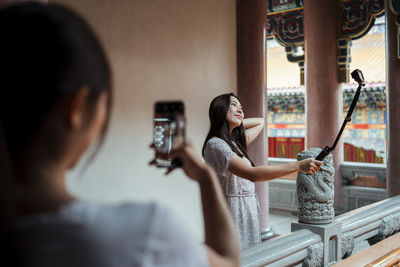 Portrait of woman photographing through smart phone