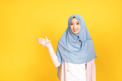 Portrait of a smiling young woman against yellow background