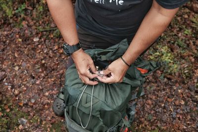 Midsection of man holding autumn leaves on field