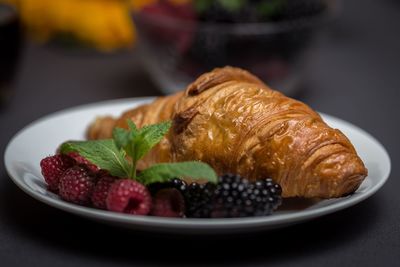 Close-up of croissant with berries in plate on table