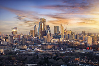 Modern buildings in city against sky during sunset