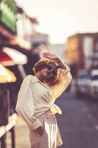 Young woman wearing sunglasses standing on street in city
