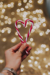 Close-up of hand holding heart shape made of illuminated christmas lights