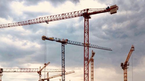 Low angle view of crane at construction site against sky