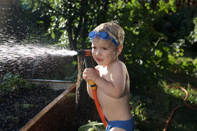 Cute boy playing with gardening hose