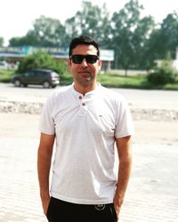 Portrait of mid adult man with hands in pockets wearing sunglasses while standing on road
