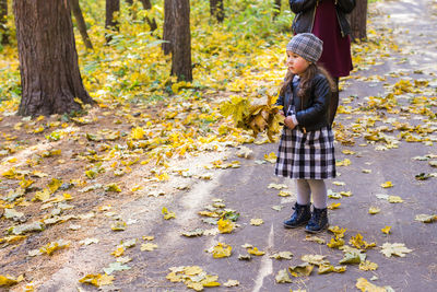Woman with umbrella walking on autumn leaves
