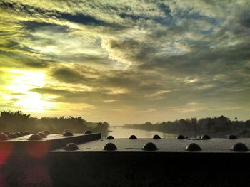 Scenic view of landscape against cloudy sky during sunset