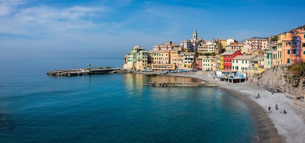 Buildings by sea against blue sky