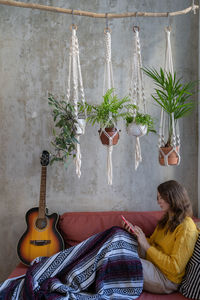 Woman sitting by potted plants at home