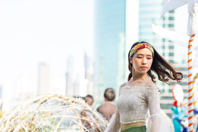 Young woman looking away while standing outdoors