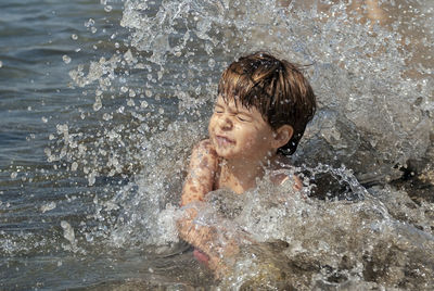 Water splashing on boy in sea