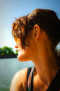 Close-up portrait of young woman looking away against sky