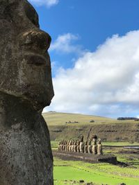 Old statues on land against sky