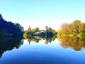 Reflection of trees in lake against clear blue sky