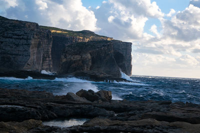 Rock formations by sea against sky