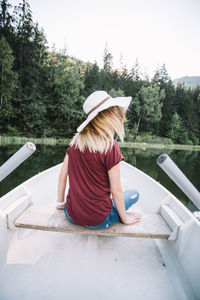 Woman with umbrella on lake against trees