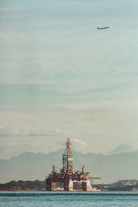 Ship in sea against cloudy sky