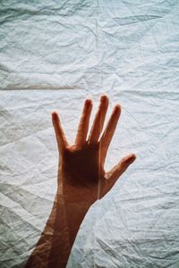 High angle view of human hand on bed