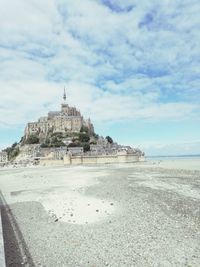 Built structure on beach against cloudy sky