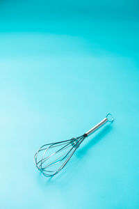 A mini balloon whisk on light blue background