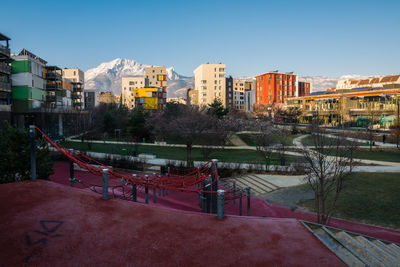 Footpath by buildings in city against clear sky