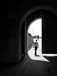 Rear view of woman walking in tunnel