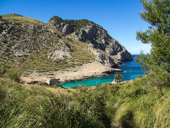 Scenic view of sea and mountains against clear blue sky