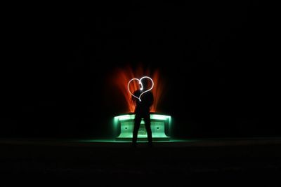 Man sitting in illuminated lamp at night