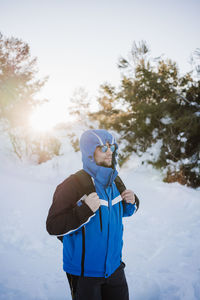 Man wearing warm clothing standing on snow covered land during winter