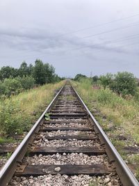 Railroad tracks by trees against sky
