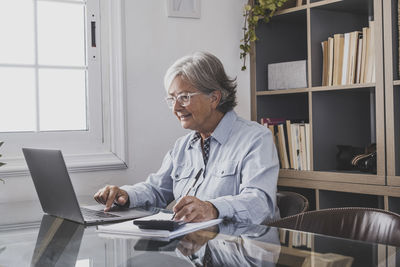 Senior woman using laptop at office
