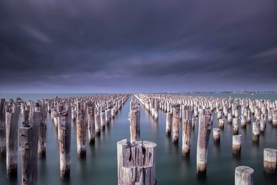 Panoramic view of wooden posts in sea against sky