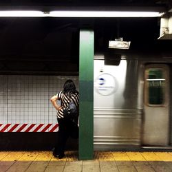 Rear view of woman standing in front of railroad station platform