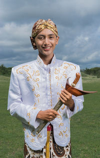 Portrait of smiling man in traditional clothes standing on field 
