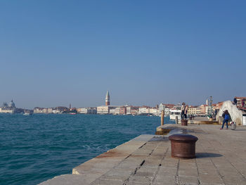 View of city at waterfront against blue sky