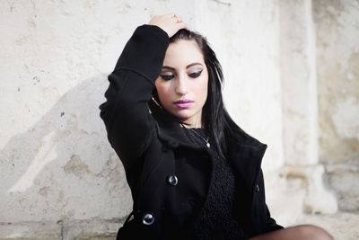 Portrait of young woman standing against wall