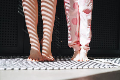 Bare feet of mom and daughter in the bathroom at home, light and shadow